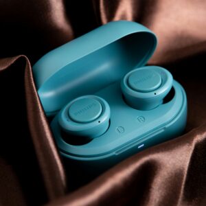 A close-up shot of wireless earbuds in a teal case set against luxurious satin fabric.